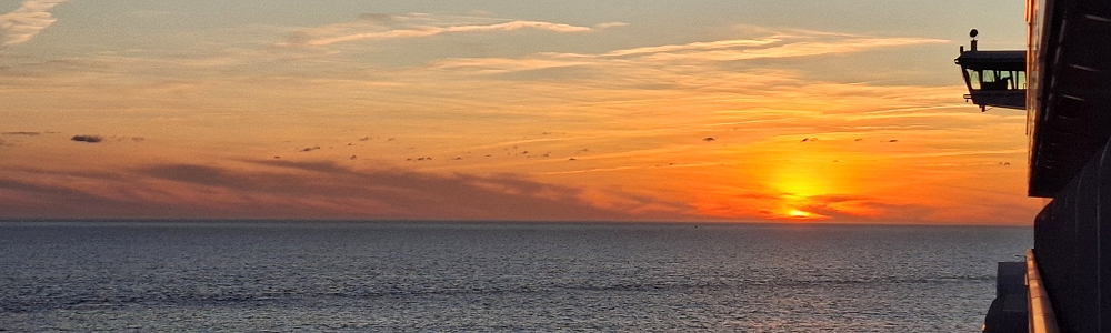 sonnenuntergang auf dem meer vom kreuzfahrtschiff aus gesehen mit blick auf die linke nock der schiffsbrücke